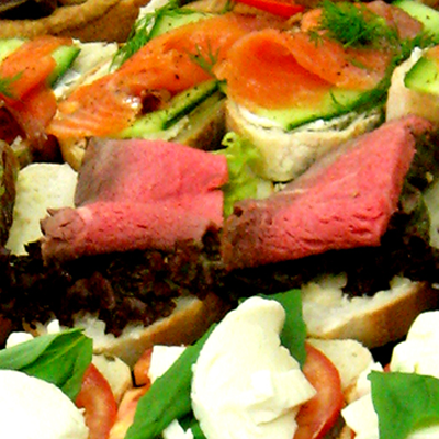 A colourful display of three open sandwich choices on a table buffet, the first cream cheese, cucumber, smoked salmon and dill; the second rare roast beef on lollo-rosso with horse radish; the last is vine tomato, basil leaf and burrata. This takes you to Working Lunches