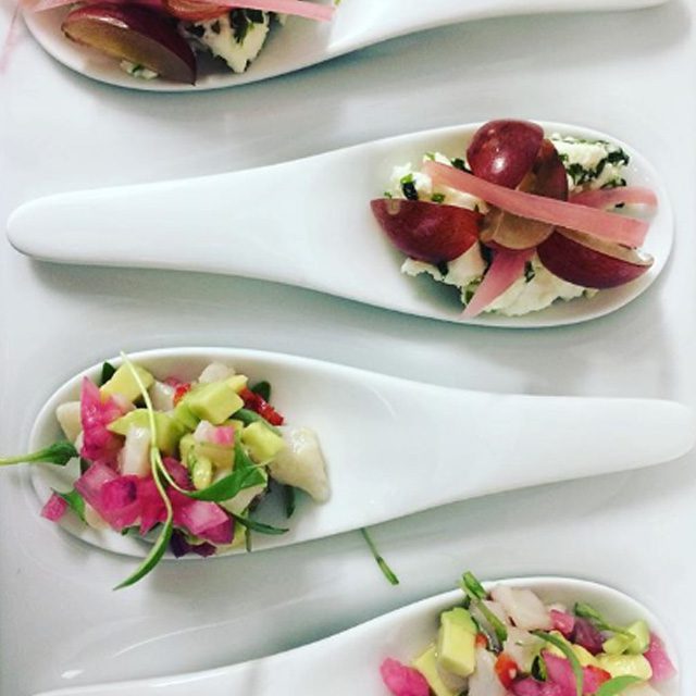 Two white China canape spoons holding colourful single bite salads, the first red grape, raspberry vinegar pickled onion and tarragon feta, the second a fresh avocado and mackerel ceviche. This will take you to our Corporate Hospitality Conference and Delegate Day options