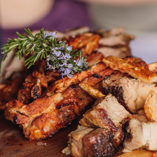 An oak board, with low and slow roasted beef long ribs with a sprig of flowering rosemary on top. Delicious, ready to serve. Here you will find our Spring/Summer menus